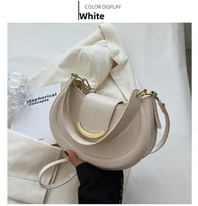 Detail of white crescent bag with golden metal buckle and sleek crossbody strap
