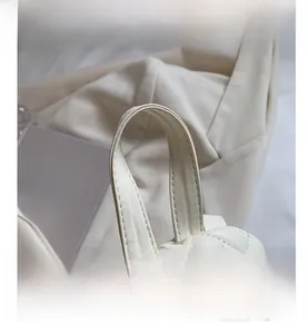 Detail view of the soft white quilted handle with refined heart embroidery on the backpack