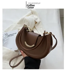 Detail of coffee brown half-moon bag with gold chain on a stylish white blazer