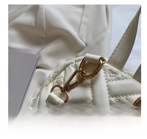 Detail of quilted heart embroidery and gold metal hook on off-white backpack