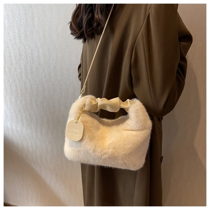 Detail of plush faux fur handbag with gold chain and pleated PU handle in beige color