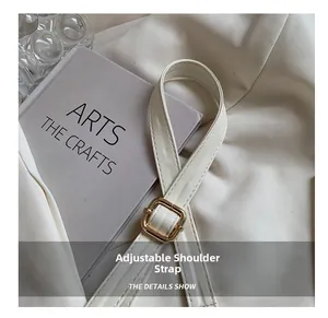 Detail shot of the adjustable white faux leather shoulder strap with a gold-tone metal buckle