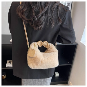 Detail of plush faux fur handbag with twisted leather handle and round charm detail