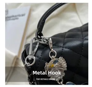 Detailed macro view of silver hardware hook and lion pendant on black quilted handbag