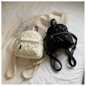 Detailed view of quilted heart pattern and gold zippers on mini faux leather backpacks