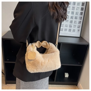 Detail of beige faux fur handbag with ruched leather handle and gold decorative tag