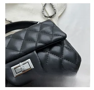 Close-up of black quilted leather shoulder bag with silver metal turn-lock and chain strap