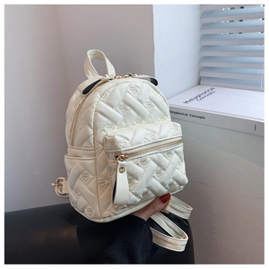 Detail of cream white mini backpack featuring quilted heart patterns and a bow