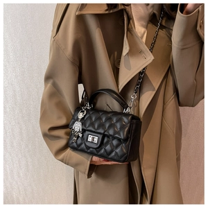 Close-up of black quilted mini bag with silver chain strap and robot charm detail