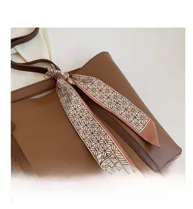 Détail du sac cabas en cuir marron avec foulard en soie géométrique sur l'anse