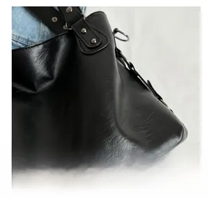 Close-up of black textured leather tote with silver rivets and D-ring buckle details