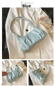 Close-up of light blue pleated croissant bag with leather texture and metal buckle detail
