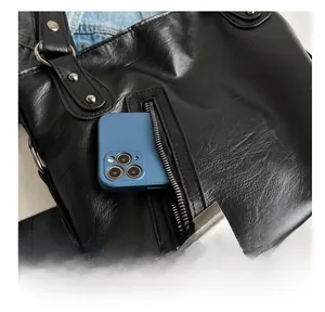 Detail of the black leather tote bag featuring a practical side zipper pocket for a smartphone