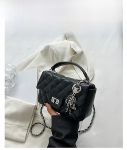 Detail of black quilted shoulder bag with silver robot charm and metal twist lock