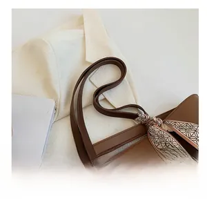 Détail d'un grand cabas en cuir marron avec foulard en soie et bandoulière confortable