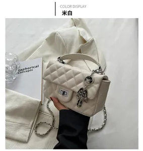 Detail of off-white quilted handbag featuring a silver twist lock and cat-shaped metal charm