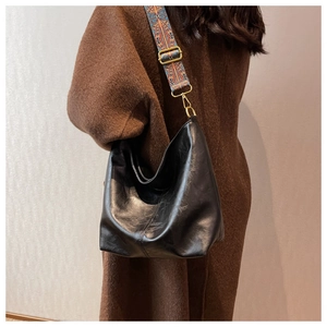 Dettaglio borsa tote in pelle PU nera con tracolla in tessuto a motivi bohémien