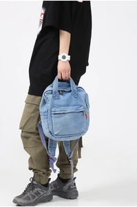 Detailed view of light blue denim backpack featuring large capacity and durable texture