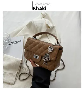 Detail of khaki quilted crossbody bag with silver chain and chic doll charm accessory