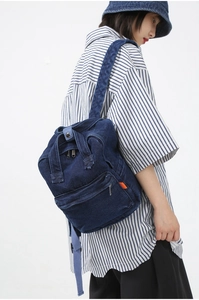 Side view of dark blue denim backpack with adjustable straps on model for daily commute