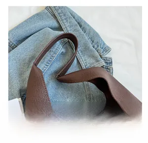 Détail de la bandoulière large en cuir souple d'un sac seau marron à grain de lychee