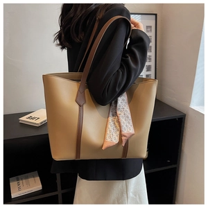 Détail du sac cabas en cuir kaki avec foulard en soie porté par un mannequin pour le quotidien
