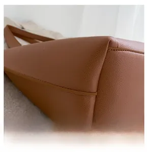 Macro detail of brown pebble grain leather tote bag with reinforced stitching and soft texture