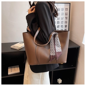 Détail d'un grand sac cabas marron avec foulard en soie porté par un mannequin en blazer