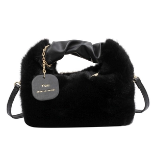 Chic black faux fur handbag with leather handle and gold lettering tag on white background