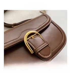 Close-up of a vintage brown leather saddle bag with a golden U-shaped metallic buckle