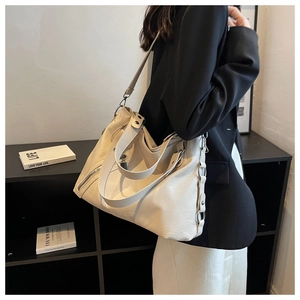 Close-up of minimalist cream leather tote bag with side zipper and metal ring detail