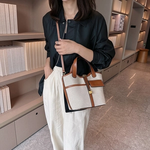 Detail of canvas and brown leather bucket bag with gold padlock and fashion logo tag