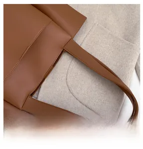 Detail of the brown PU leather tote handle with fine stitching and lychee texture