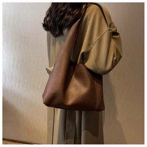 Détail du sac cabas en cuir marron foncé montrant la texture et la bandoulière profilée