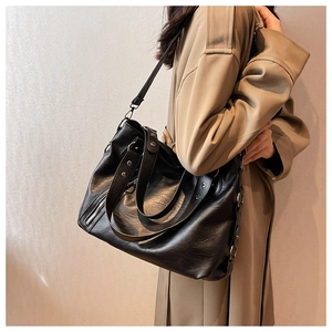 Side view of large black leather tote bag with silver zipper detail and shoulder strap
