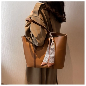 Détail d'un grand sac cabas marron orné d'un foulard en soie à imprimé géométrique chic