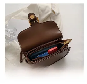 Internal view of dark brown saddle bag showing spacious multi-layer storage and gold lock