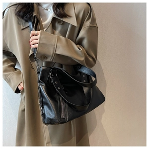 Detailed view of black PU leather tote bag with vertical zipper and wide shoulder strap