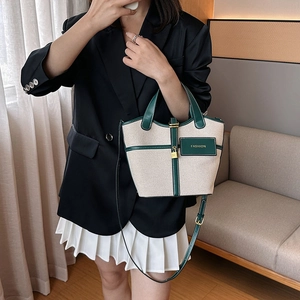Close-up of canvas and green leather bucket bag with metallic buckle and FASHION tag