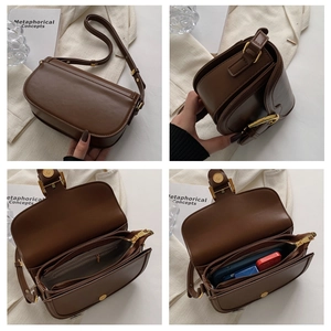 Detailed interior of brown faux leather saddle bag with three compartments and gold buckles