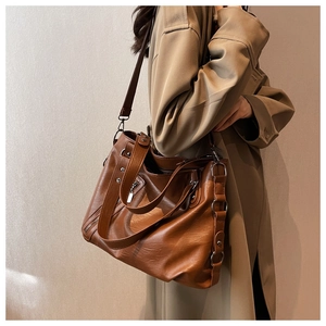 Detailed view of brown textured leather tote bag on shoulder with metal ring details