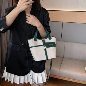 Detail of canvas tote bag with green leather trim, metal lock and fashion charm