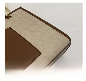 Détail du sac cabas beige tissé avec bordure en cuir marron et anneaux en métal doré
