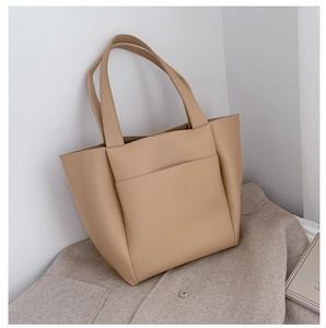 Detailed macro view of cream PU leather tote bag with exterior pocket on gray coat