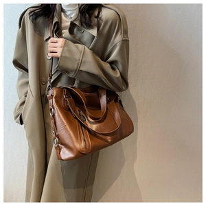 Detail of a brown large capacity tote bag with adjustable straps and metal ring buckles