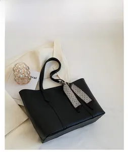 Détail d'un grand sac cabas noir avec ruban géométrique sur fond blanc