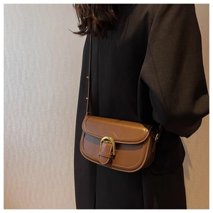 Brown vintage saddle bag detail showing golden D-buckle on a black blazer model background