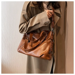 Brown faux leather tote bag worn by a model in a trench coat for size reference