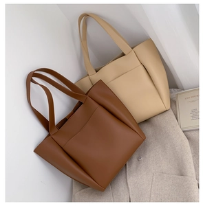Detail of soft PU leather tote bags in brown and beige with front pockets for work