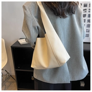 Vue détaillée de la texture du motif litchi beige sur le sac à main seau minimaliste